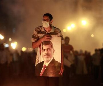 File photo of an injured supporter of deposed Egyptian President Mohamed Mursi carrying a poster of Mursi as they run from tear gas fired by riot police during clashes on the Sixth of October Bridge over the Ramsis square area in central Cairo Analysis: Setbacks to bring quieter Qatar foreign policy but no U-turn