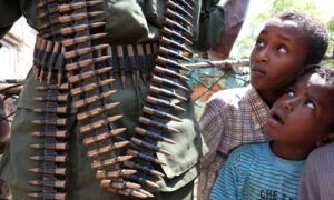 Somali children look at a soldier on patrol