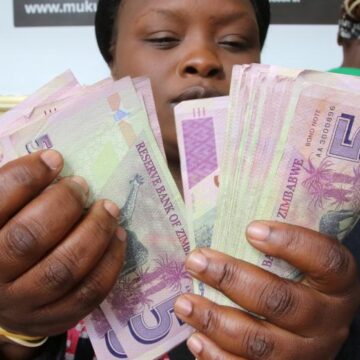 FILE PHOTO: A currency dealer counts wads of bond notes outside a bank in Harare Mugabe’s Zimbabwe gets busy creating ‘fiction money’